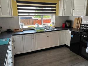 a kitchen with white cabinets and a sink and a window at Central Mablethorpe Apartment in Mablethorpe +5 photos