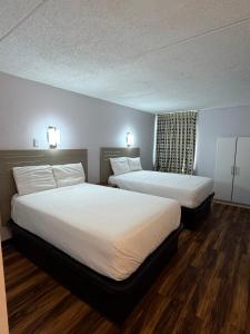 two beds in a hotel room with wood floors at Noble Suites in Albany