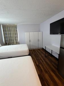 a room with two beds and a flat screen tv at Noble Suites in Albany