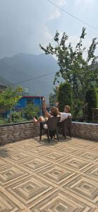 two people sitting in chairs on a patio at House of Brahma Kasol in Kasol