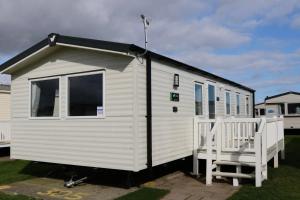 a small white tiny house with a porch at Saltwinds - Camber Sands in Camber