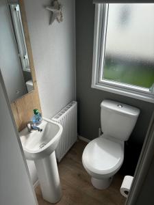 a bathroom with a white toilet and a sink at Saltwinds - Camber Sands in Camber +9 photos