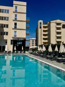 a pool with chairs and umbrellas next to a hotel at Hotel Iliria in Golem