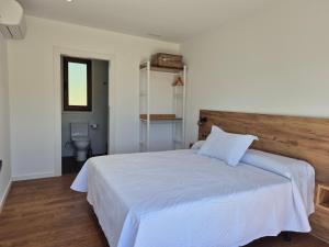 a bedroom with a white bed with a wooden headboard at Pensión Agro da Porta in Palas de Rei +11 photos