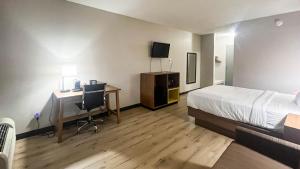 a bedroom with a bed and a desk with a computer at Studio 6 Suites Fremont, OH in Fremont