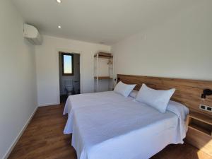 a bedroom with a white bed with white sheets and pillows at Pensión Agro da Porta in Palas de Rei