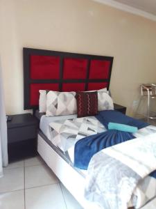 a bedroom with a large bed with a red headboard at MOFFAT GUEST HOUSE in Randfontein +6 photos