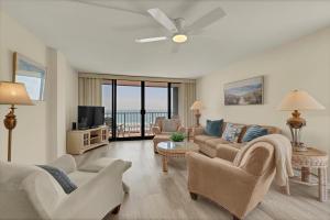 a living room with a couch and chairs and a tv at Station One - 6K by Sea Scape Properties in Wrightsville Beach