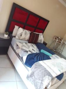 a bed with a red headboard and pillows on it at MOFFAT GUEST HOUSE in Randfontein