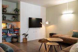 a living room with a couch and a tv on a wall at Het Kasterhuis - Groepsverblijf in Wetteren +49 photos