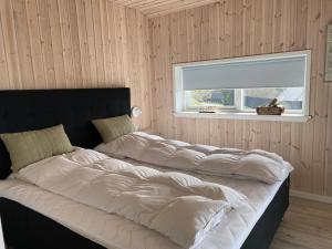a large bed in a room with a window at Udsigten over Hjarbæk in Løgstrup