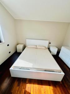 a large white bed in a room with wooden floors at Mamisà 4 - appartamenti e camere private con bagno in Schio