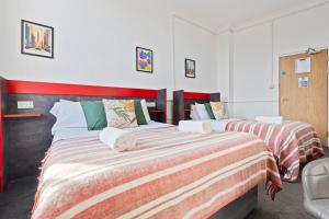 two beds in a bedroom with red and white sheets at Modern Self-Contained Studio in Dudley Sleeps 2 in Dudley