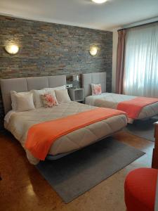 a bedroom with two beds and a brick wall at Hotel Santa Apolonia in Bragança
