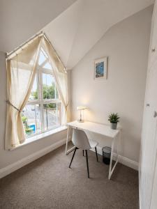 a white desk with a chair and a window at Waterford Triangle Apartment in Waterford