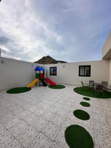 a patio with a playground with a table and chairs at Bee House in Taif