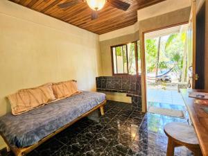 a bedroom with a bed and a table and a window at Don Jon's Surf and Yoga Lodge in Santa Teresa Beach