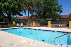 a swimming pool with two white chairs in front of a building at Fairview Inn & Suites Mobile in Mobile