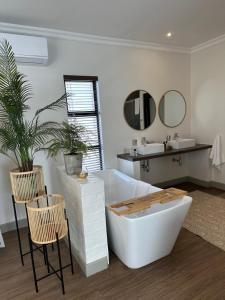 a bathroom with a tub and two chairs and a sink at Pepper Tree Venue & Guesthouse in Bloemfontein +62 photos