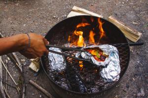a person cooking food over a fire in a grill at Sundance By Basecamp in Kananaskis Village