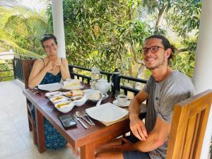 a man and a woman sitting at a table with food at Turtle Moon Lodge in Rekawa