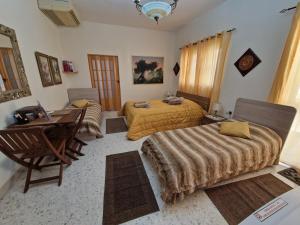 a bedroom with two beds and a table and a desk at Saracini's Homestay in Attard