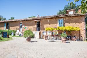 a brick building with tables and chairs in front of it at Les chalets de fiolles in Brens