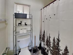 a bathroom with a toilet and a shower curtain with trees at Mountain View Buck Deer Cabinette in Alto