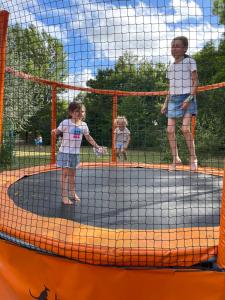 a man and two children playing on a trampoline at Les chalets de fiolles in Brens
