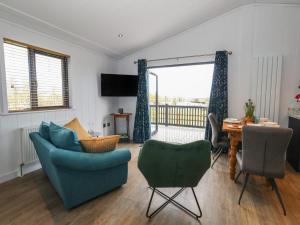 a living room with a blue couch and chairs and a table at Grass Roots in Temple Combe
