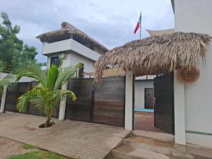 a house with a thatched roof and a palm tree at Casa Xolococo in Brisas de Zicatela
