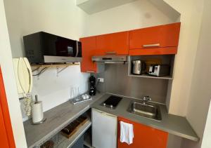 a small kitchen with orange cabinets and a sink at Studio cosy Amiens in Amiens +2 photos