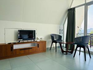 a living room with a tv and two chairs and a table at Wilmora in Ramakkalmedu