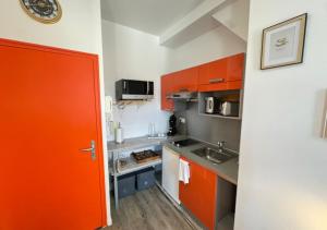 a kitchen with an orange door and a sink at Studio cosy Amiens in Amiens