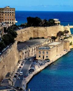 a city with cars parked on a road next to the water at Saracini's Homestay in Attard