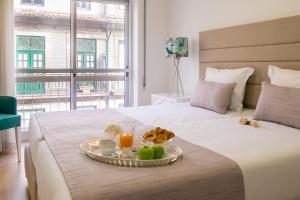 a bed with a tray of food on it at Simon Guest Apartments in Porto