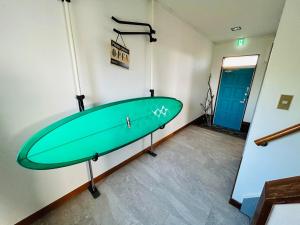 a green surfboard on display in a room at K'sVILLAGE 平砂浦ハウスＳ in Tateyama