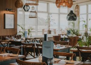 a restaurant with wooden tables and chairs and windows at P1 The Warren Abersoch in Llanbedrog