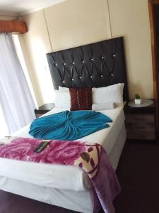 a bedroom with a large bed with a black headboard at MOFFAT GUEST HOUSE in Randfontein