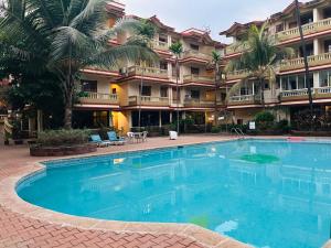 a large swimming pool in front of a hotel at Lilly candolim apartment in Candolim
