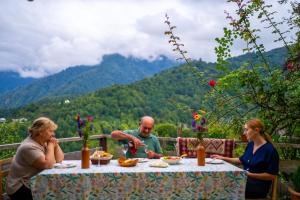 a group of people sitting at a table eating food at Guest House Mokvare in Gundauri