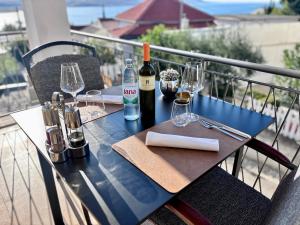 a table with wine bottles and glasses on a balcony at Rooms & Pansion Odmor in Rovanjska
