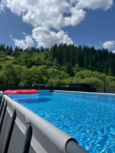 a large swimming pool with blue water at Boiko house - котеджі з чаном-джакузі та басейном in Slavske