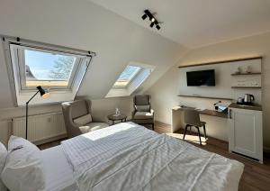 a bedroom with a bed and two chairs and a desk at Hotel Landhaus Steinfeld in Greetsiel +38 photos