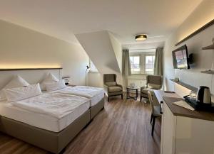 a hotel room with a bed and a desk and chairs at Hotel Landhaus Steinfeld in Greetsiel