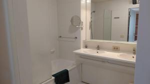 a white bathroom with a sink and a mirror at Kamerverhuur Bascule in Roeselare