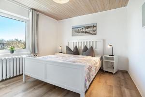 a white bedroom with a bed and a window at Ferienwohnung Wulf in Groß Zicker