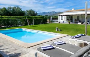 a swimming pool with two chairs and a house at Les Herbetes in Port de Pollensa