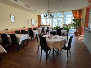 a dining room with tables and chairs and a chandelier at pepb Schulungshotel in Sarstedt
