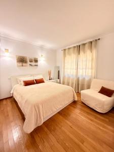 a white bedroom with a large bed and a couch at Horizonte da Vinha in Santo Tirso